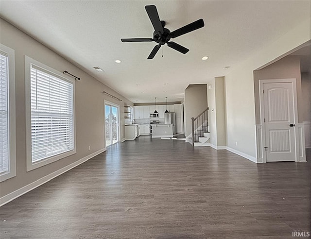 unfurnished living room featuring a textured ceiling, ceiling fan, and dark wood-type flooring