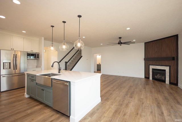 kitchen featuring appliances with stainless steel finishes, ceiling fan, pendant lighting, a center island with sink, and white cabinetry