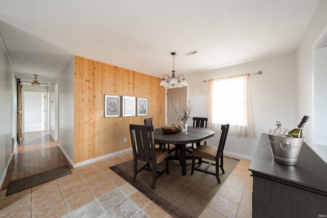 dining area featuring wood walls and a chandelier