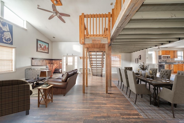 living room with ceiling fan, a towering ceiling, and dark wood-type flooring