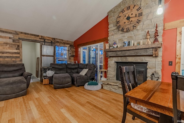 living room with a stone fireplace, high vaulted ceiling, and hardwood / wood-style flooring