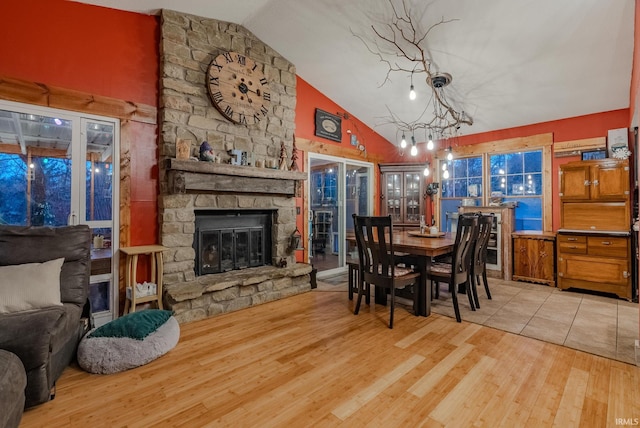 dining space with a chandelier, a fireplace, high vaulted ceiling, and light hardwood / wood-style flooring