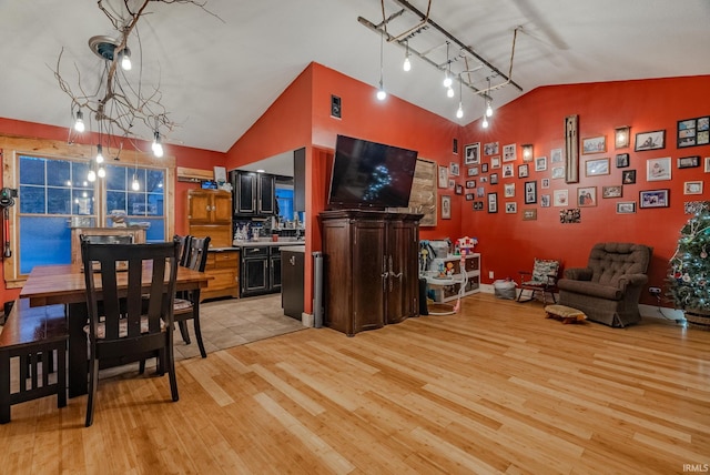 dining area featuring light wood-type flooring, high vaulted ceiling, and an inviting chandelier