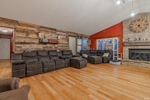 living room with a fireplace, hardwood / wood-style floors, a barn door, and wooden walls