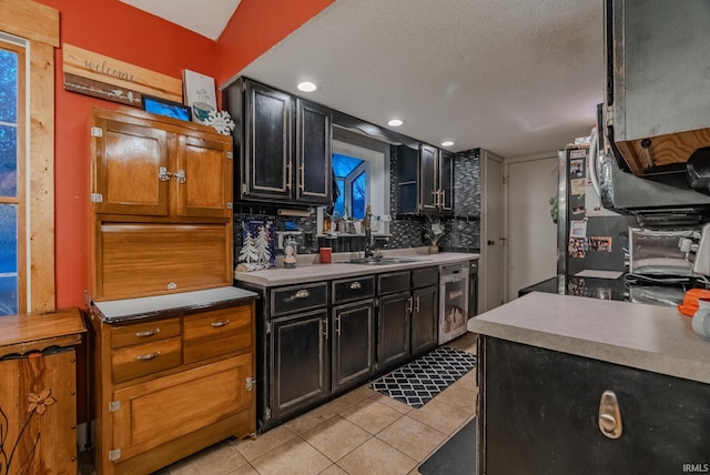 kitchen featuring backsplash, sink, a textured ceiling, light tile patterned flooring, and beverage cooler