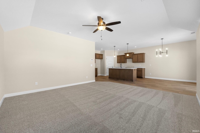 10209 Buckshire Ct, New Haven, IN 46774 - unfurnished living room featuring light colored carpet, ceiling fan, a chandelier, baseboards, and vaulted ceiling
