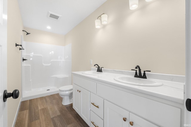 bathroom featuring hardwood / wood-style flooring, a shower, toilet, and vanity