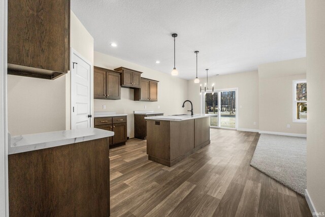 10209 Buckshire Ct, New Haven, IN 46774 - kitchen with dark wood-style flooring, a sink, a kitchen island with sink, a chandelier, and light countertops