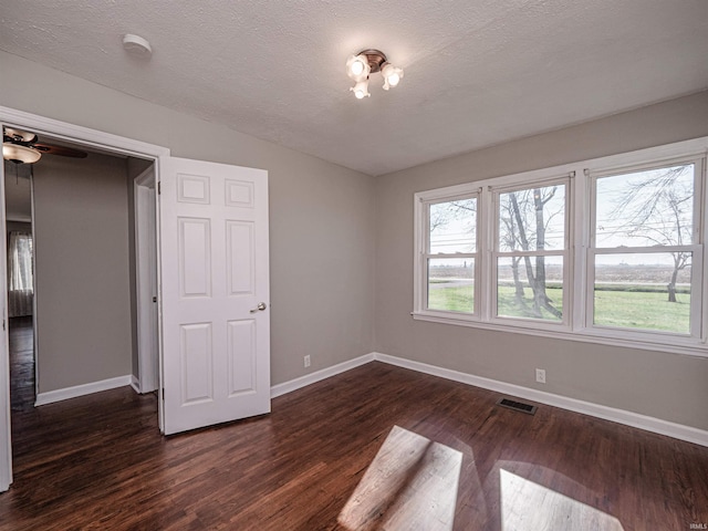 unfurnished bedroom with dark hardwood / wood-style floors and a textured ceiling