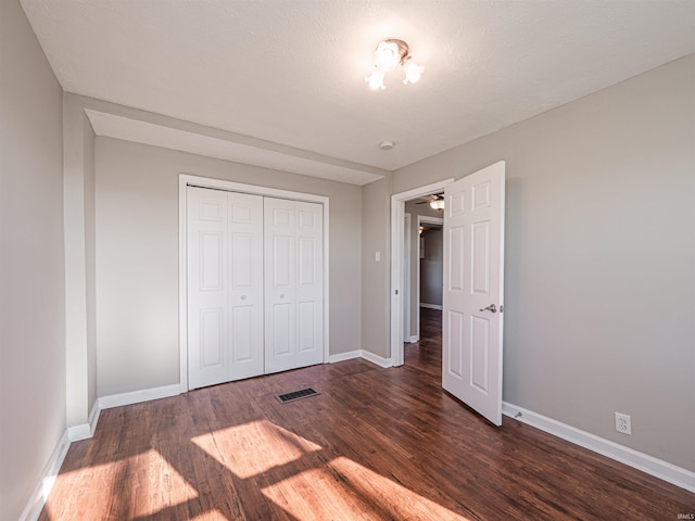 unfurnished bedroom featuring dark hardwood / wood-style flooring, a textured ceiling, and a closet