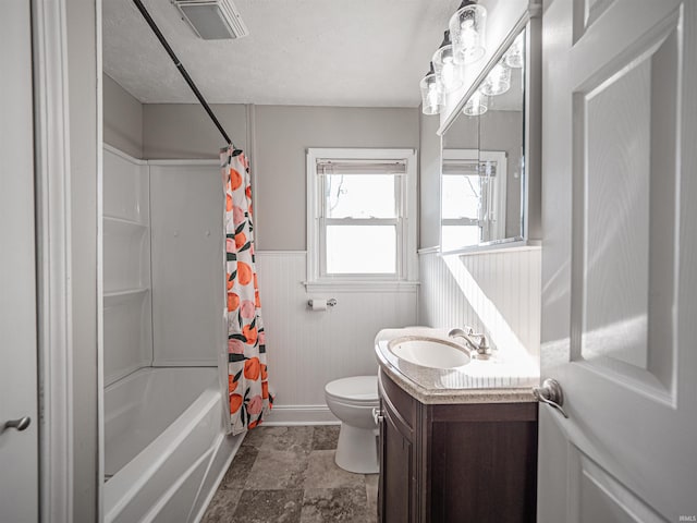 full bathroom with a textured ceiling, vanity, wooden walls, shower / bath combo with shower curtain, and toilet