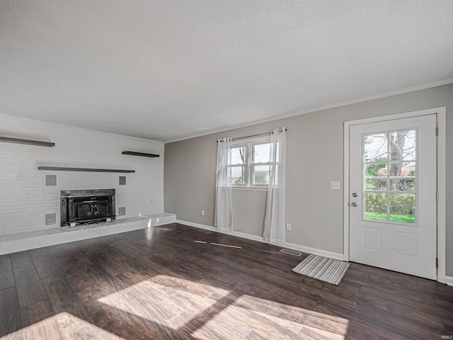 unfurnished living room with plenty of natural light, dark hardwood / wood-style flooring, ornamental molding, and a fireplace