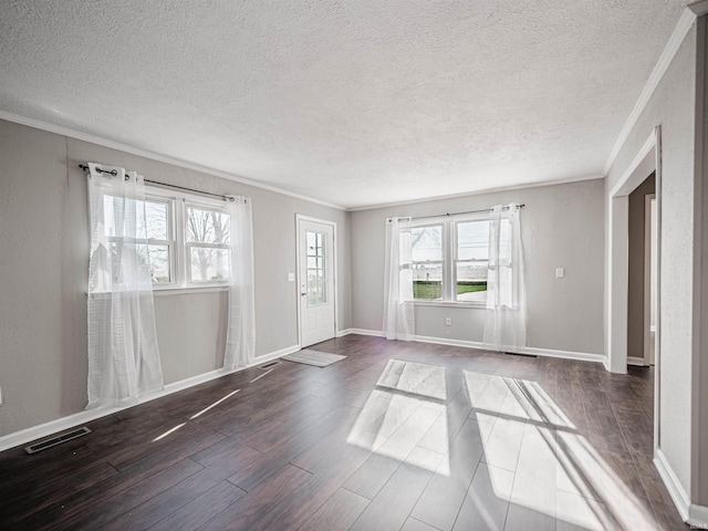 spare room with a textured ceiling, ornamental molding, and dark wood-type flooring