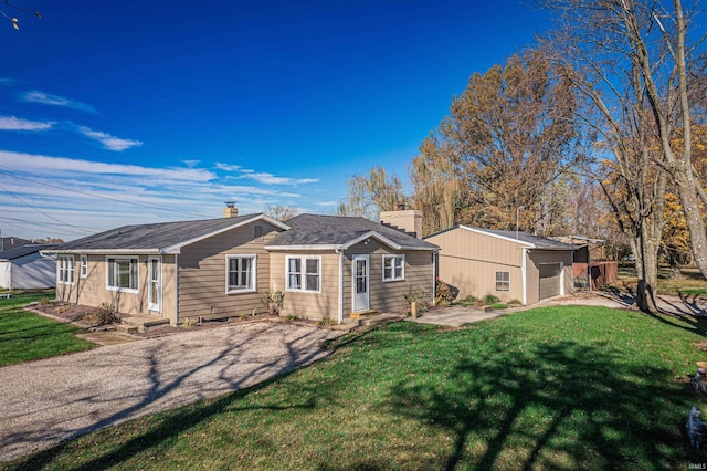 rear view of house featuring an outbuilding, a garage, and a lawn