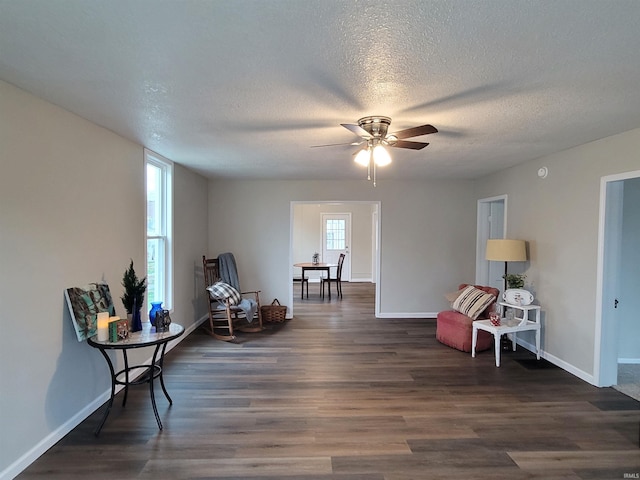 living area with dark hardwood / wood-style floors, ceiling fan, and a textured ceiling