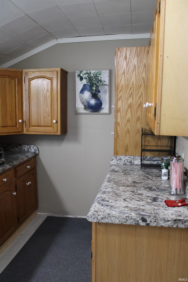 kitchen with carpet, light stone counters, and vaulted ceiling