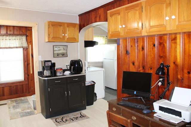 kitchen with wood walls, white fridge, ornamental molding, and light hardwood / wood-style flooring