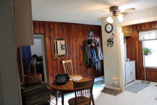 dining room featuring ceiling fan, wood walls, and light hardwood / wood-style floors