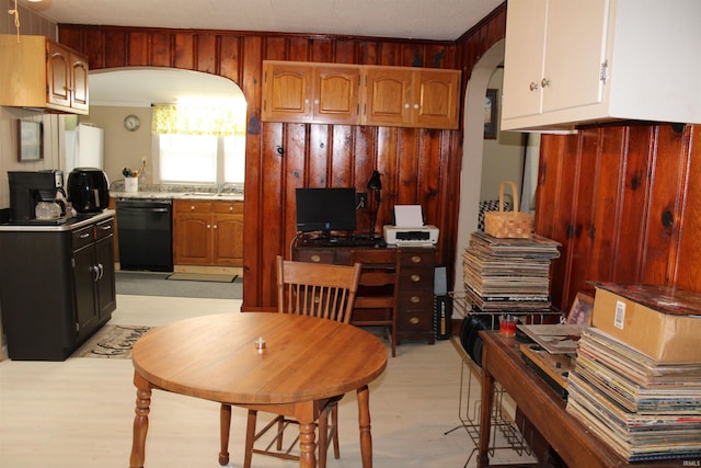 kitchen with dishwasher, sink, and wood walls