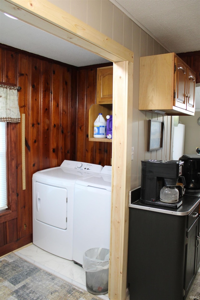 laundry room with wood walls and separate washer and dryer