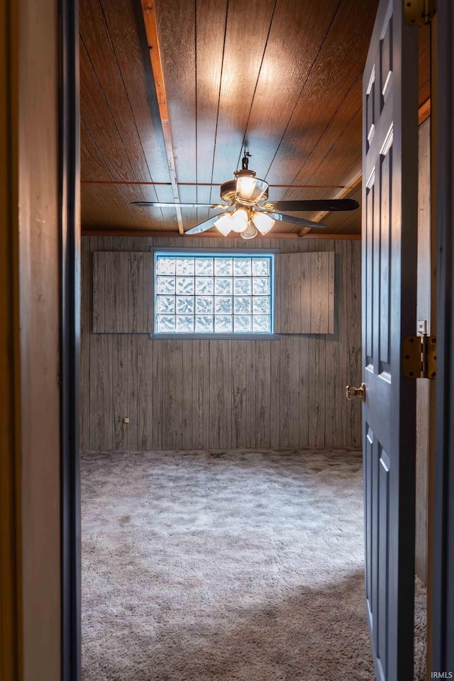 unfurnished room featuring carpet flooring, wood walls, ceiling fan, and wood ceiling