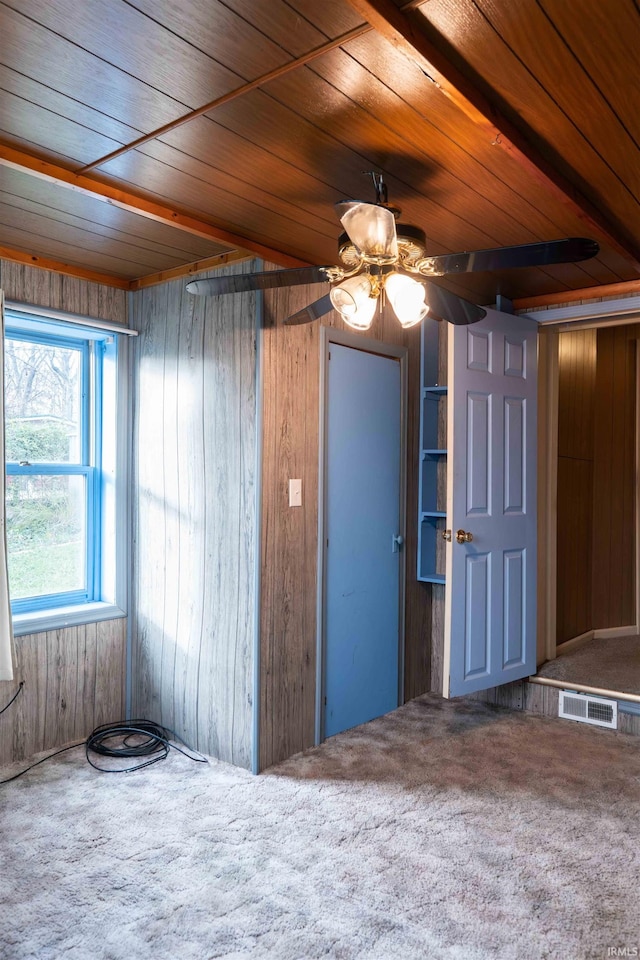 carpeted empty room featuring wood walls, ceiling fan, and wooden ceiling