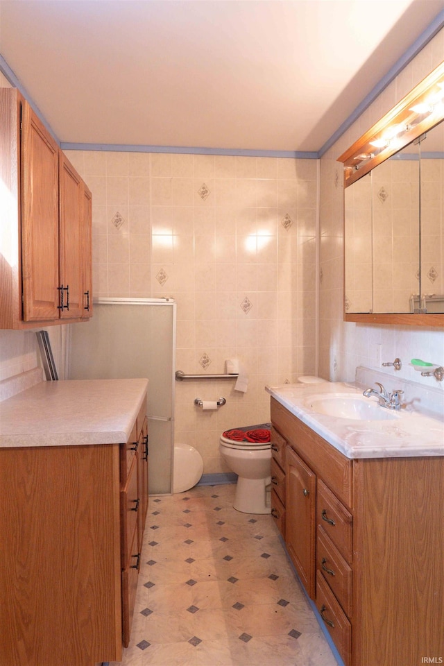 bathroom with vanity, toilet, and tile walls