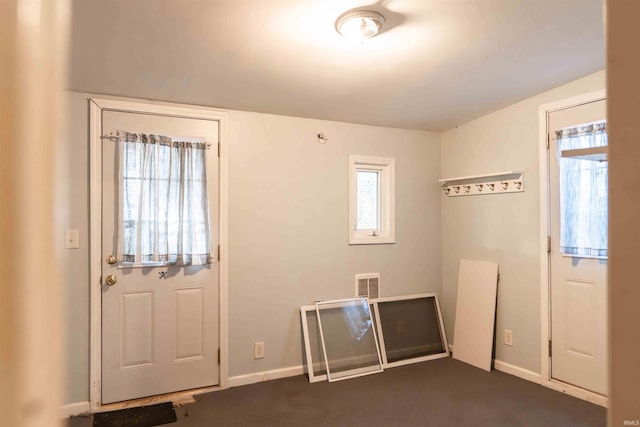 entrance foyer featuring dark carpet and plenty of natural light