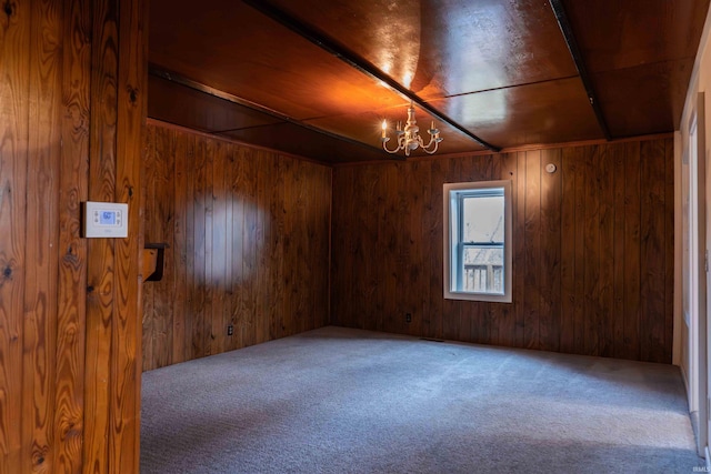 carpeted spare room with an inviting chandelier and wooden walls