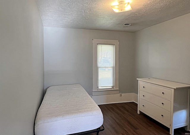 bedroom featuring dark hardwood / wood-style flooring and a textured ceiling