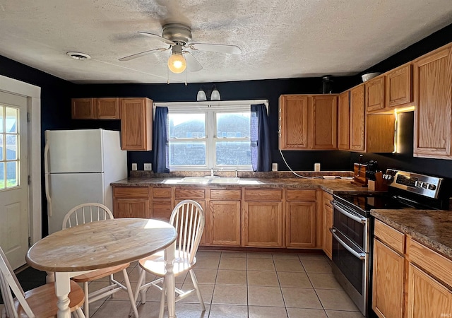 kitchen featuring stainless steel electric range, light tile patterned flooring, sink, a textured ceiling, and white fridge