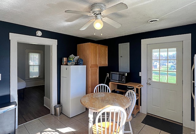 kitchen with electric panel, a textured ceiling, ceiling fan, light tile patterned floors, and white fridge