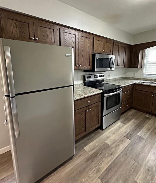 kitchen featuring dark brown cabinetry, light hardwood / wood-style flooring, and stainless steel appliances