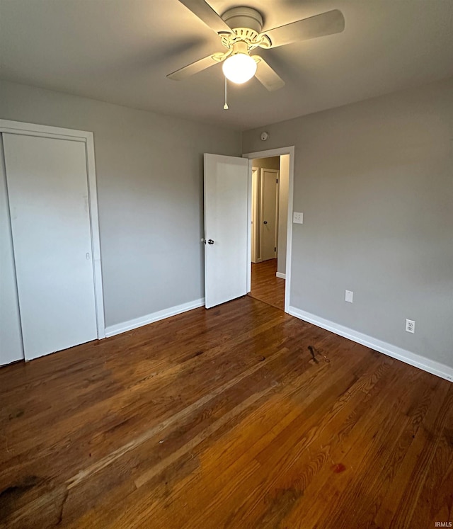 unfurnished bedroom with dark hardwood / wood-style flooring, a closet, and ceiling fan