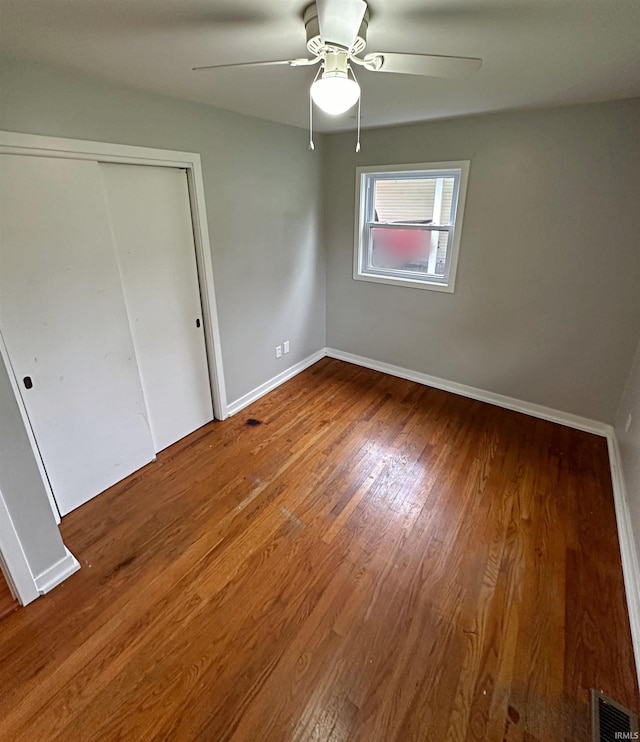 unfurnished bedroom with wood-type flooring, a closet, and ceiling fan