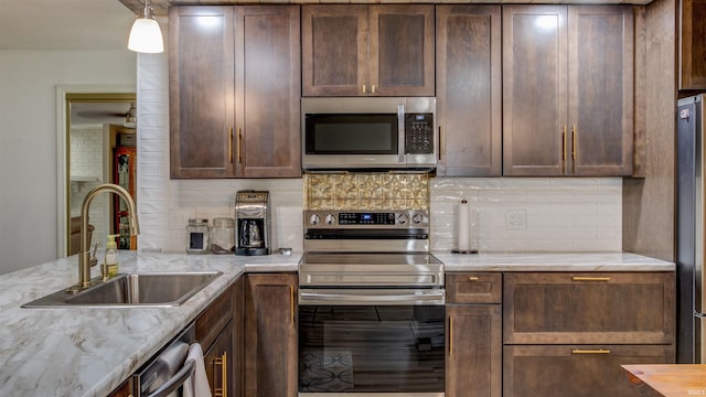 kitchen featuring decorative backsplash, stainless steel appliances, light stone counters, and sink