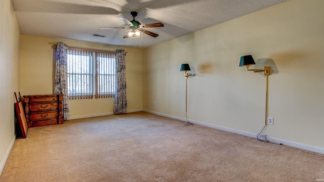 empty room featuring ceiling fan, light colored carpet, and a textured ceiling