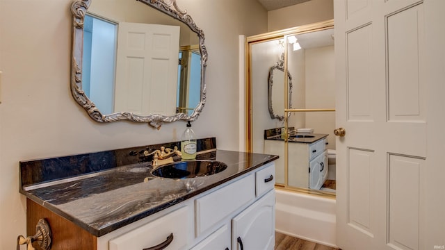 bathroom with vanity, hardwood / wood-style flooring, and bath / shower combo with glass door