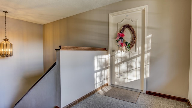 entryway featuring carpet flooring, a textured ceiling, and an inviting chandelier