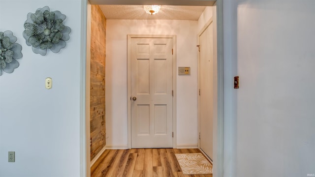 doorway to outside featuring a textured ceiling and light hardwood / wood-style flooring