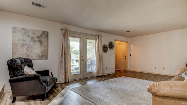 interior space with hardwood / wood-style floors, a textured ceiling, and french doors