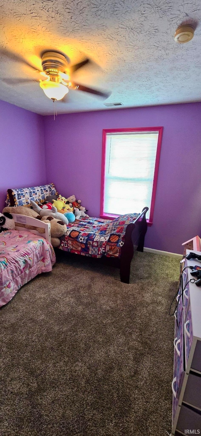 carpeted bedroom featuring ceiling fan and a textured ceiling