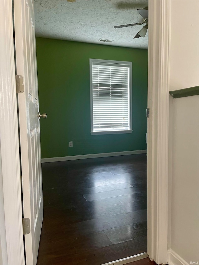 unfurnished room featuring ceiling fan, dark hardwood / wood-style flooring, and a textured ceiling