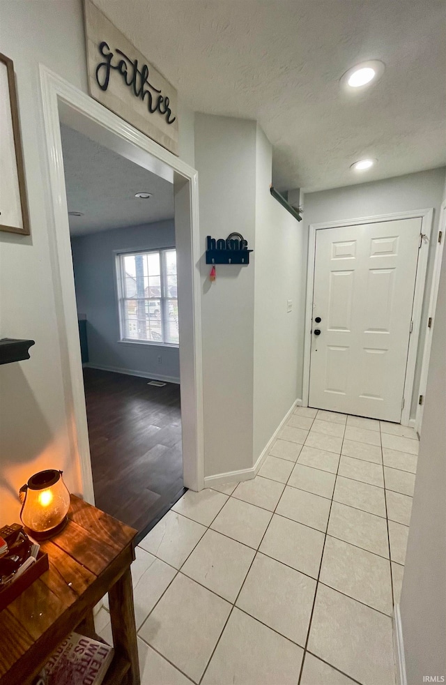 corridor with light hardwood / wood-style floors and a textured ceiling