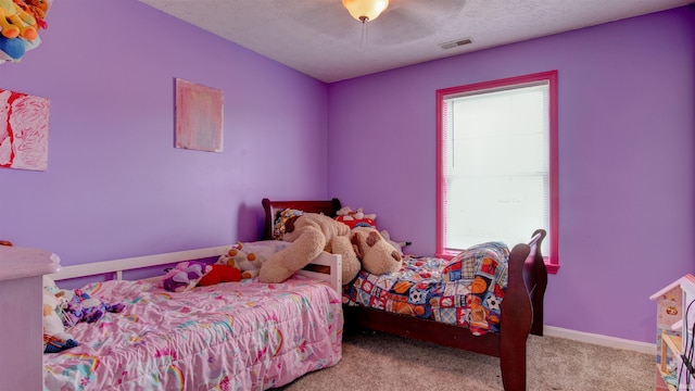 carpeted bedroom with a textured ceiling, multiple windows, and ceiling fan