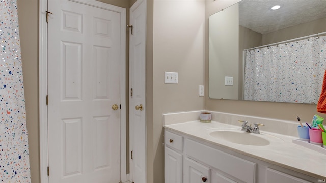 bathroom with a shower with curtain, vanity, and a textured ceiling