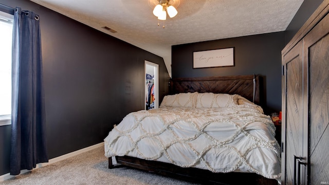 carpeted bedroom with ceiling fan, a closet, and a textured ceiling