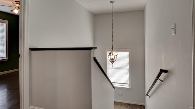 staircase featuring hardwood / wood-style flooring, a textured ceiling, and a chandelier