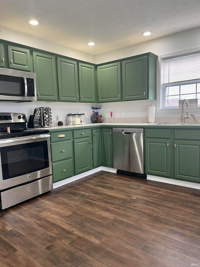 kitchen featuring appliances with stainless steel finishes, dark hardwood / wood-style flooring, a textured ceiling, and green cabinetry