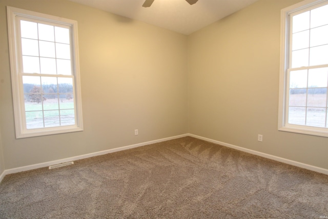 carpeted spare room featuring plenty of natural light and ceiling fan